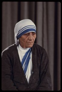 A color photograph of Mother Teresa in her characteristic blue and white habit.